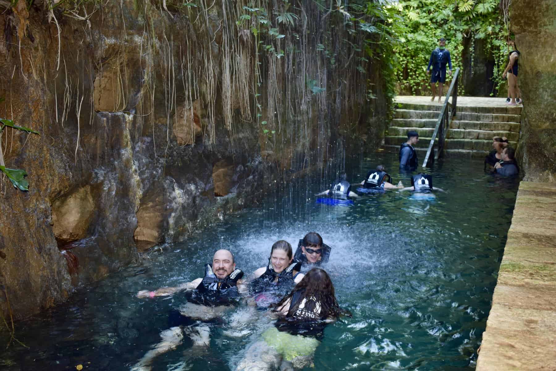 People under a waterfall at hacienda mucuyche