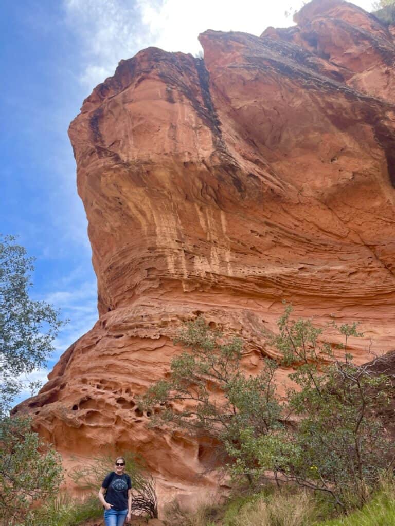 Woman standing in front of large red rock.