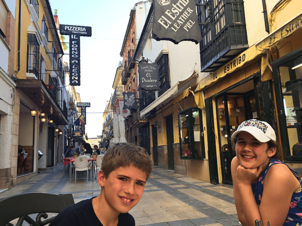 A boy and a girl smiling while sitting at a table in Ronda, Spain