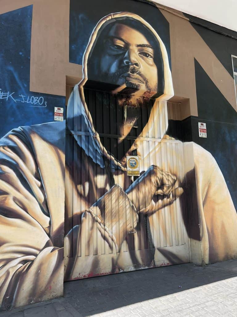 Street art of a man wearing a hoodie and holding his fist to his heart