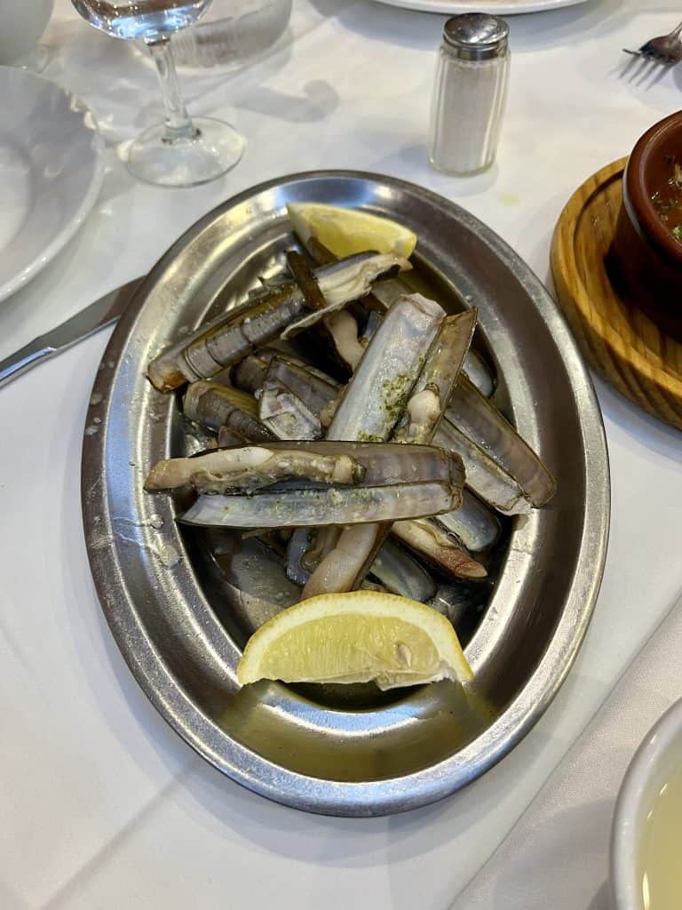 Razor clams on a dish with two slices of lemon