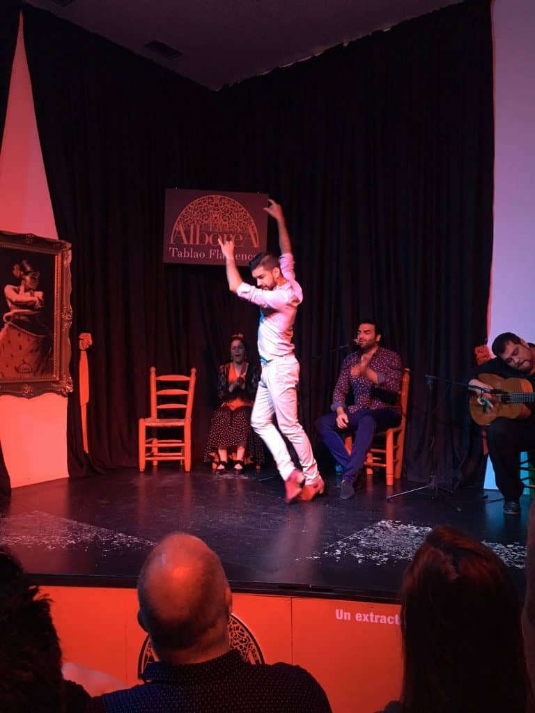 Man in white outfit dances flamenco on a stage